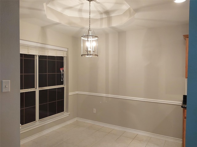 unfurnished room featuring a chandelier and a tray ceiling