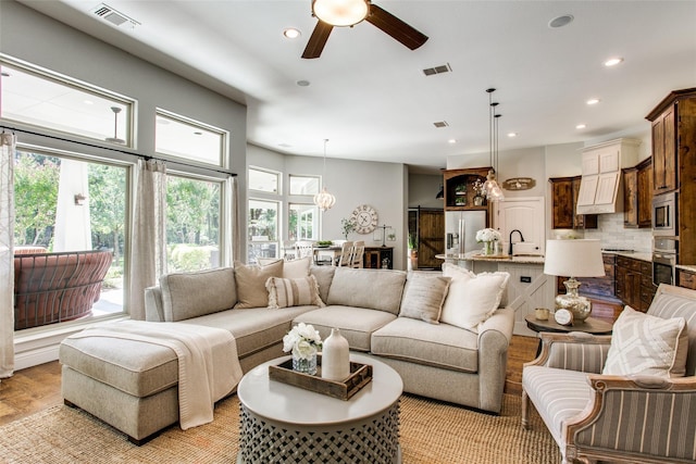 living room with sink, light hardwood / wood-style floors, and ceiling fan