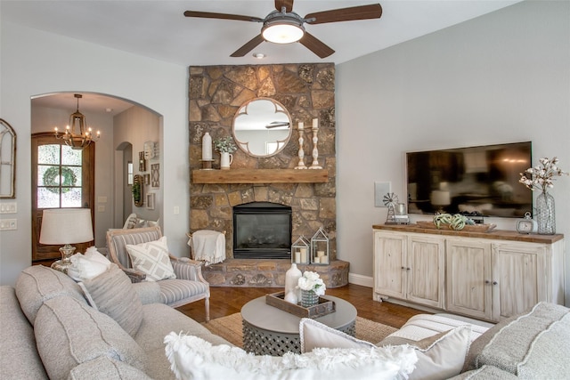 living room featuring ceiling fan with notable chandelier, a fireplace, and wood-type flooring