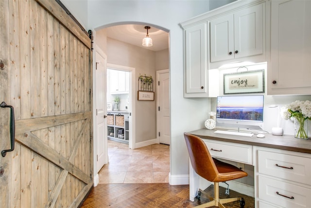 home office featuring a barn door and light hardwood / wood-style flooring