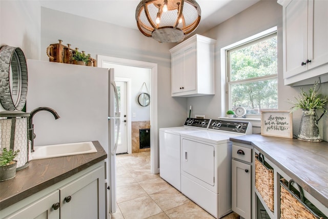 laundry area featuring cabinets, light tile patterned floors, sink, and independent washer and dryer