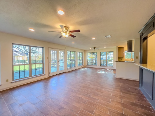 unfurnished living room with a textured ceiling and ceiling fan