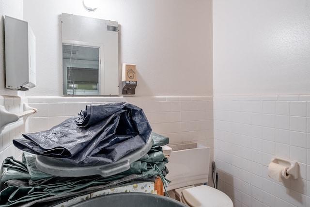 bathroom featuring tile walls and toilet