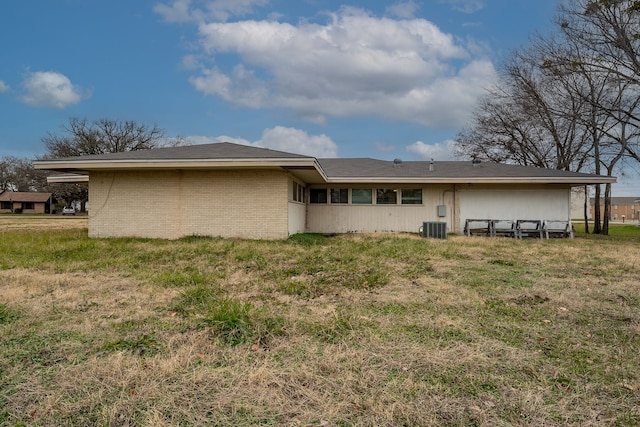 rear view of property featuring cooling unit and a yard