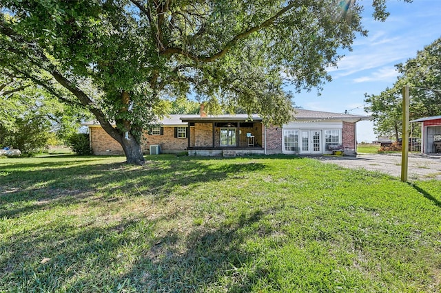 view of front of home featuring brick siding, french doors, and a front lawn