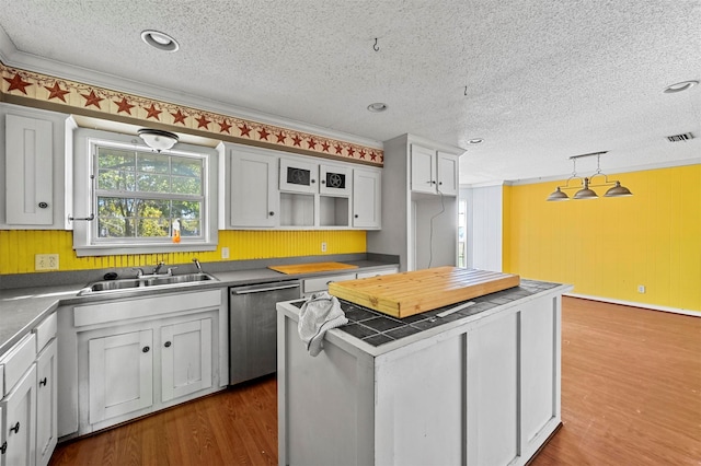 kitchen featuring hanging light fixtures, stainless steel dishwasher, wood-type flooring, and crown molding