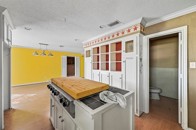 kitchen featuring pendant lighting, a textured ceiling, ornamental molding, and light hardwood / wood-style floors