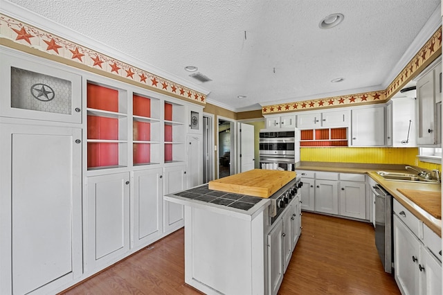 kitchen with white cabinetry, hardwood / wood-style floors, sink, a center island, and appliances with stainless steel finishes