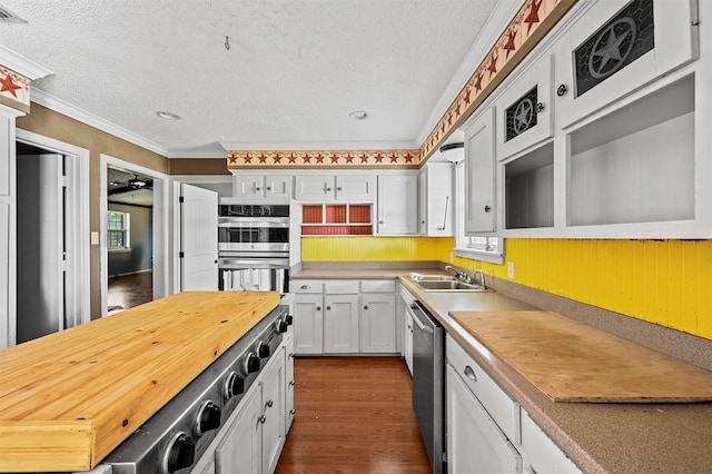 kitchen with white cabinetry, crown molding, appliances with stainless steel finishes, a textured ceiling, and dark wood-type flooring