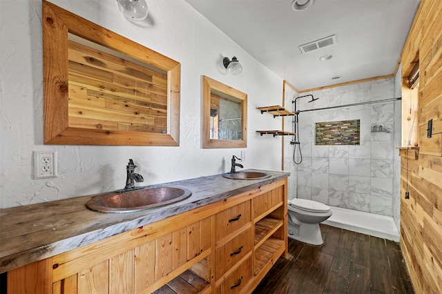 bathroom featuring tiled shower, double vanity, hardwood / wood-style flooring, and toilet