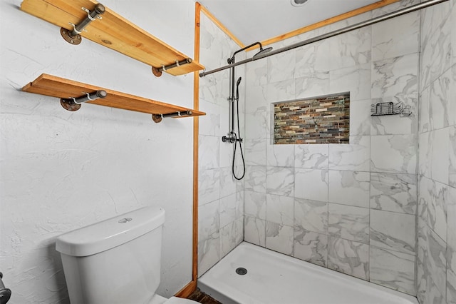 bathroom with a tile shower and toilet