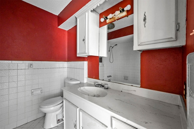 bathroom featuring tile walls, a textured ceiling, toilet, tile patterned floors, and vanity