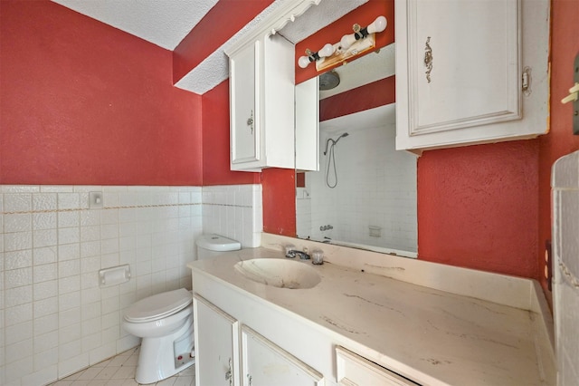 bathroom featuring a textured ceiling, toilet, vanity, tile walls, and tile patterned floors