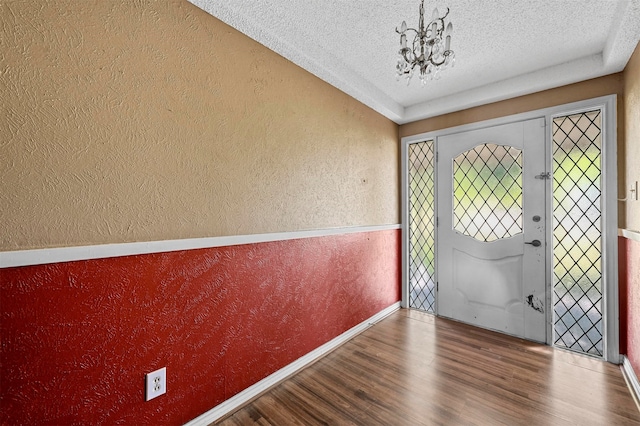 entryway with an inviting chandelier, a textured ceiling, and hardwood / wood-style floors