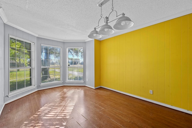 unfurnished dining area featuring ornamental molding, wood-type flooring, a textured ceiling, and a chandelier