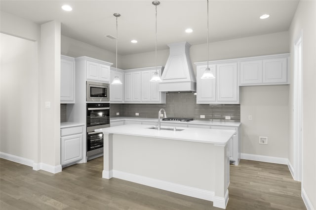 kitchen with appliances with stainless steel finishes, custom range hood, backsplash, light wood-type flooring, and white cabinets