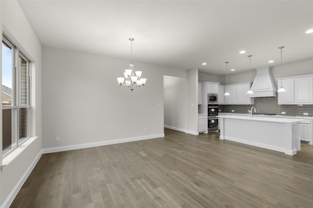 kitchen featuring white cabinetry, backsplash, premium range hood, and wood-type flooring