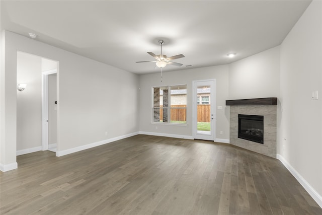 unfurnished living room with ceiling fan, a tiled fireplace, and hardwood / wood-style flooring