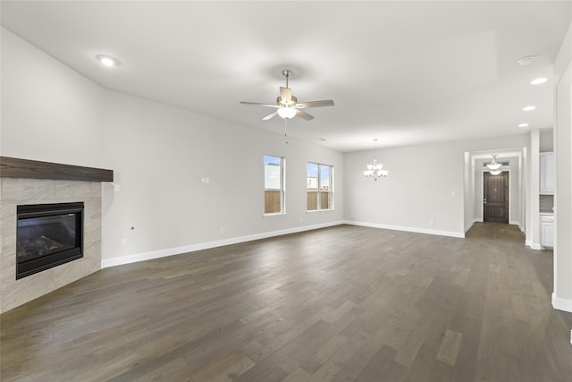 unfurnished living room featuring a fireplace, ceiling fan with notable chandelier, and dark hardwood / wood-style flooring