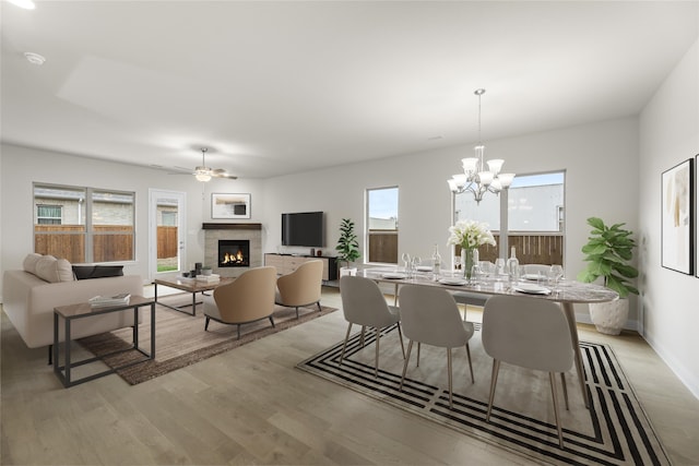 dining room with ceiling fan with notable chandelier and light wood-type flooring