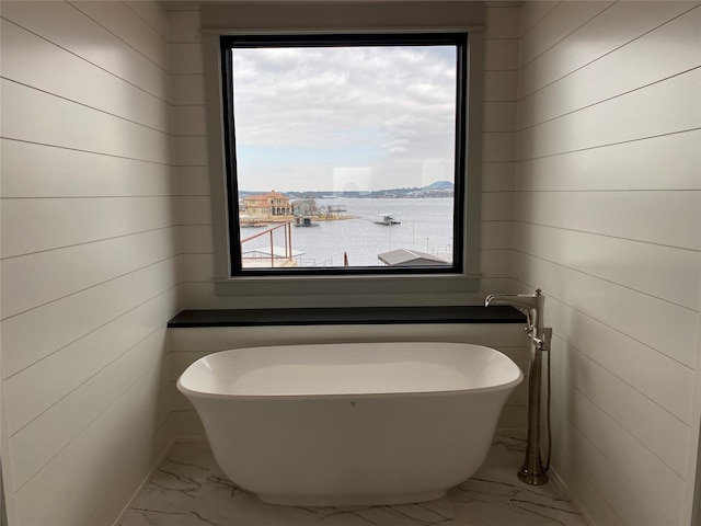 bathroom featuring a tub and a water view