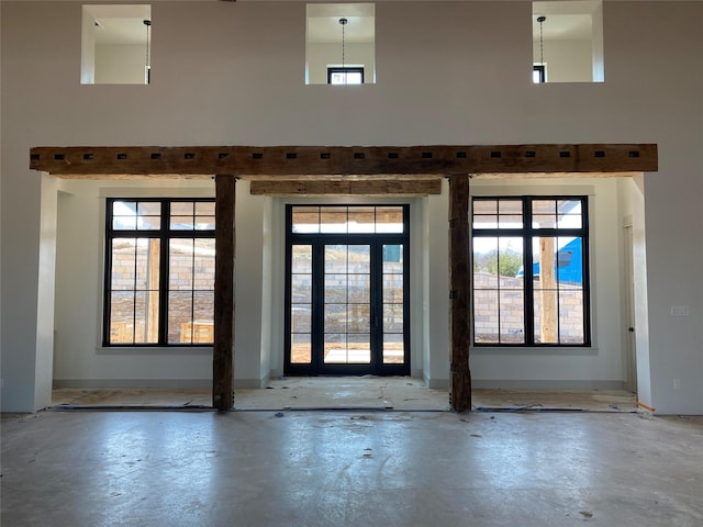 doorway featuring concrete flooring, a high ceiling, and a healthy amount of sunlight