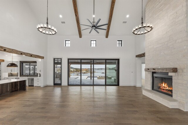 unfurnished living room with high vaulted ceiling, beam ceiling, and a stone fireplace