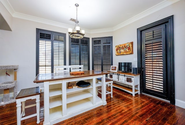 dining room featuring dark wood-type flooring, ornamental molding, and a chandelier