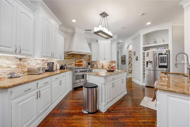 kitchen featuring stainless steel appliances, premium range hood, tasteful backsplash, white cabinetry, and a center island