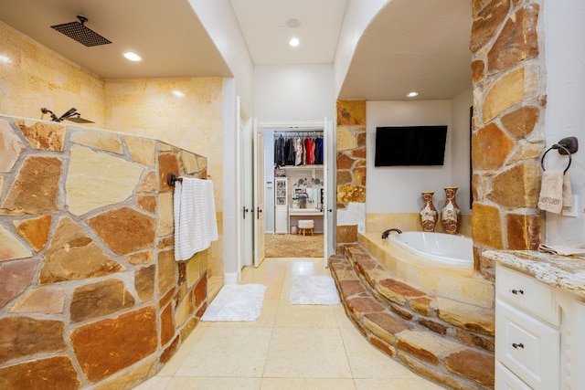 bathroom featuring tiled tub, tile floors, and vanity