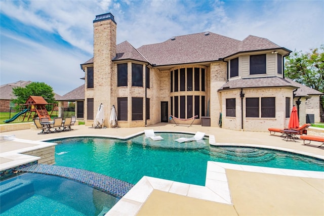 view of swimming pool featuring pool water feature, a patio area, an in ground hot tub, and a playground