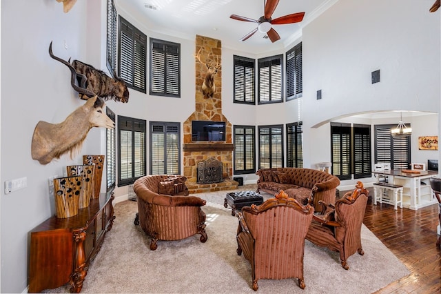 living room featuring a fireplace, ceiling fan with notable chandelier, hardwood / wood-style floors, and plenty of natural light