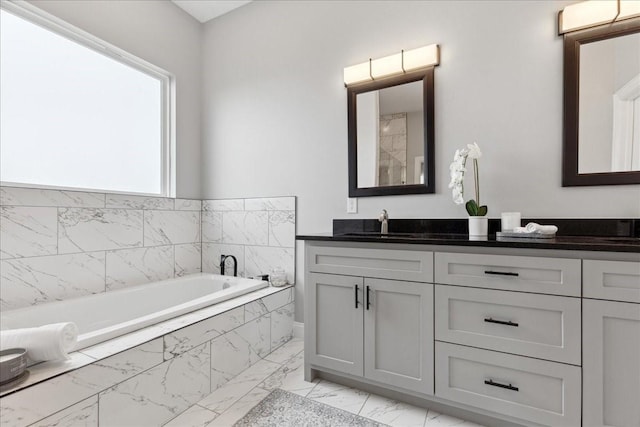 bathroom with a relaxing tiled tub and vanity