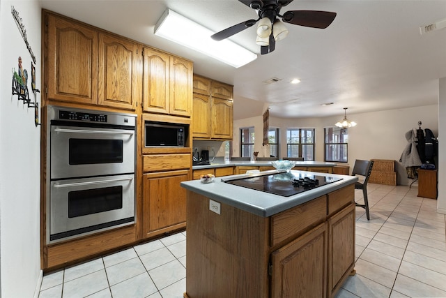 kitchen featuring light tile patterned floors, visible vents, a kitchen island, brown cabinets, and black appliances