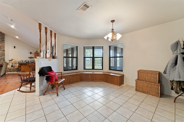 interior space featuring a chandelier, light tile patterned flooring, lofted ceiling, and visible vents