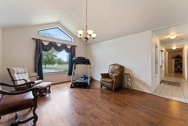 living area with vaulted ceiling, baseboards, wood finished floors, and a notable chandelier