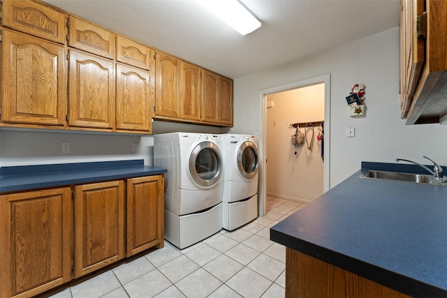 washroom featuring cabinet space, light tile patterned floors, separate washer and dryer, and a sink