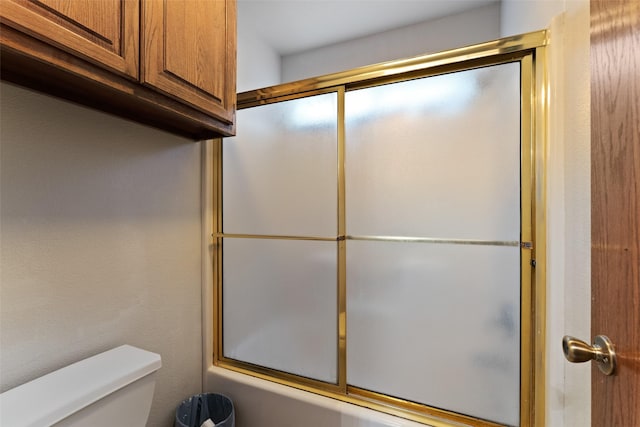 bathroom with combined bath / shower with glass door and toilet