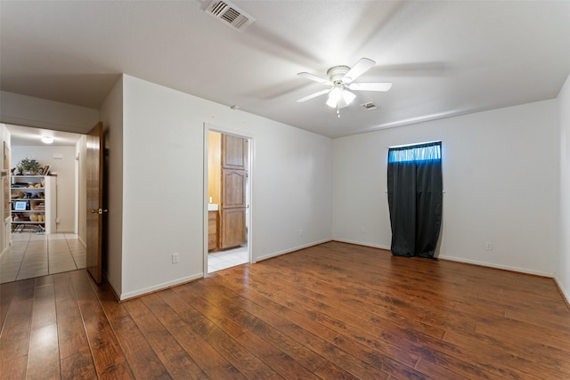 empty room featuring dark wood-style flooring, visible vents, ceiling fan, and baseboards