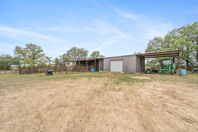 view of yard featuring driveway, a detached garage, an outbuilding, fence, and a pole building