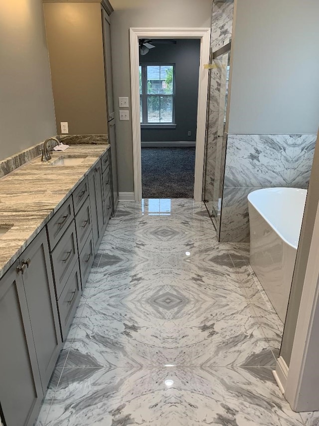 bathroom featuring vanity, a tub, and tile walls