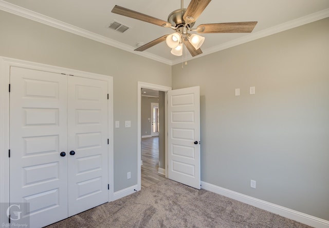 unfurnished bedroom with ceiling fan, a closet, ornamental molding, and light carpet