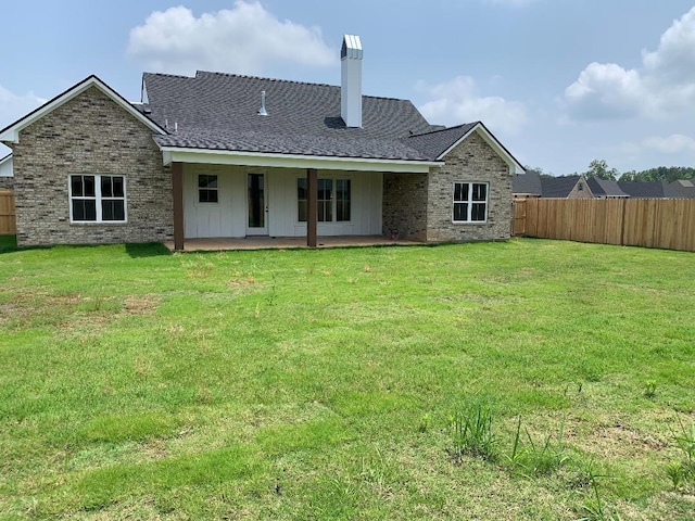 back of house with a lawn and a patio