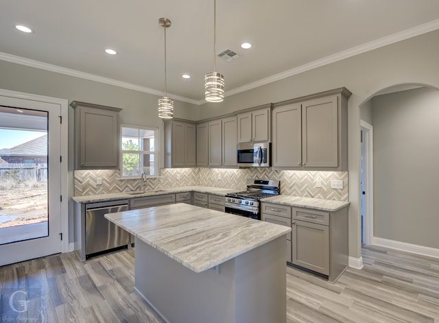 kitchen featuring appliances with stainless steel finishes, pendant lighting, sink, gray cabinetry, and a center island