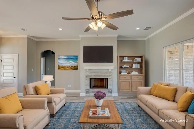 living room with hardwood / wood-style flooring, crown molding, and a fireplace