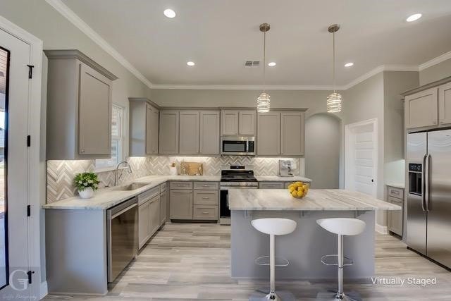 kitchen featuring pendant lighting, sink, gray cabinets, appliances with stainless steel finishes, and a kitchen island