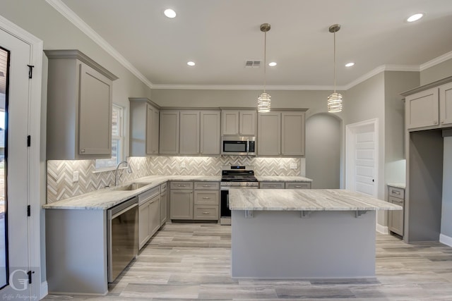 kitchen featuring sink, gray cabinetry, stainless steel appliances, a kitchen island, and decorative light fixtures