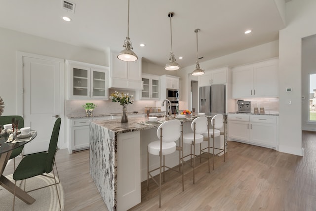 kitchen with white cabinets, a center island with sink, and stainless steel appliances