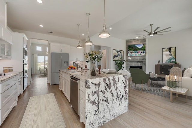 kitchen featuring sink, stainless steel appliances, white cabinetry, and a center island with sink