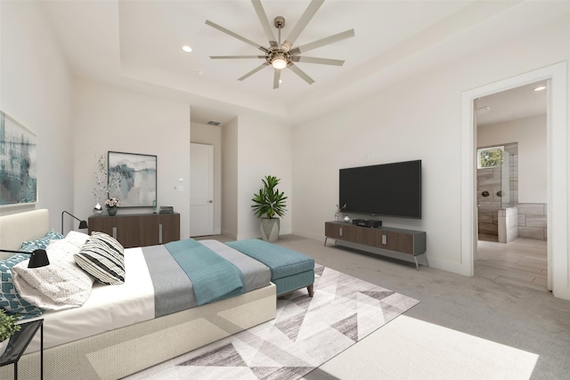 bedroom with ensuite bath, light colored carpet, ceiling fan, and a tray ceiling